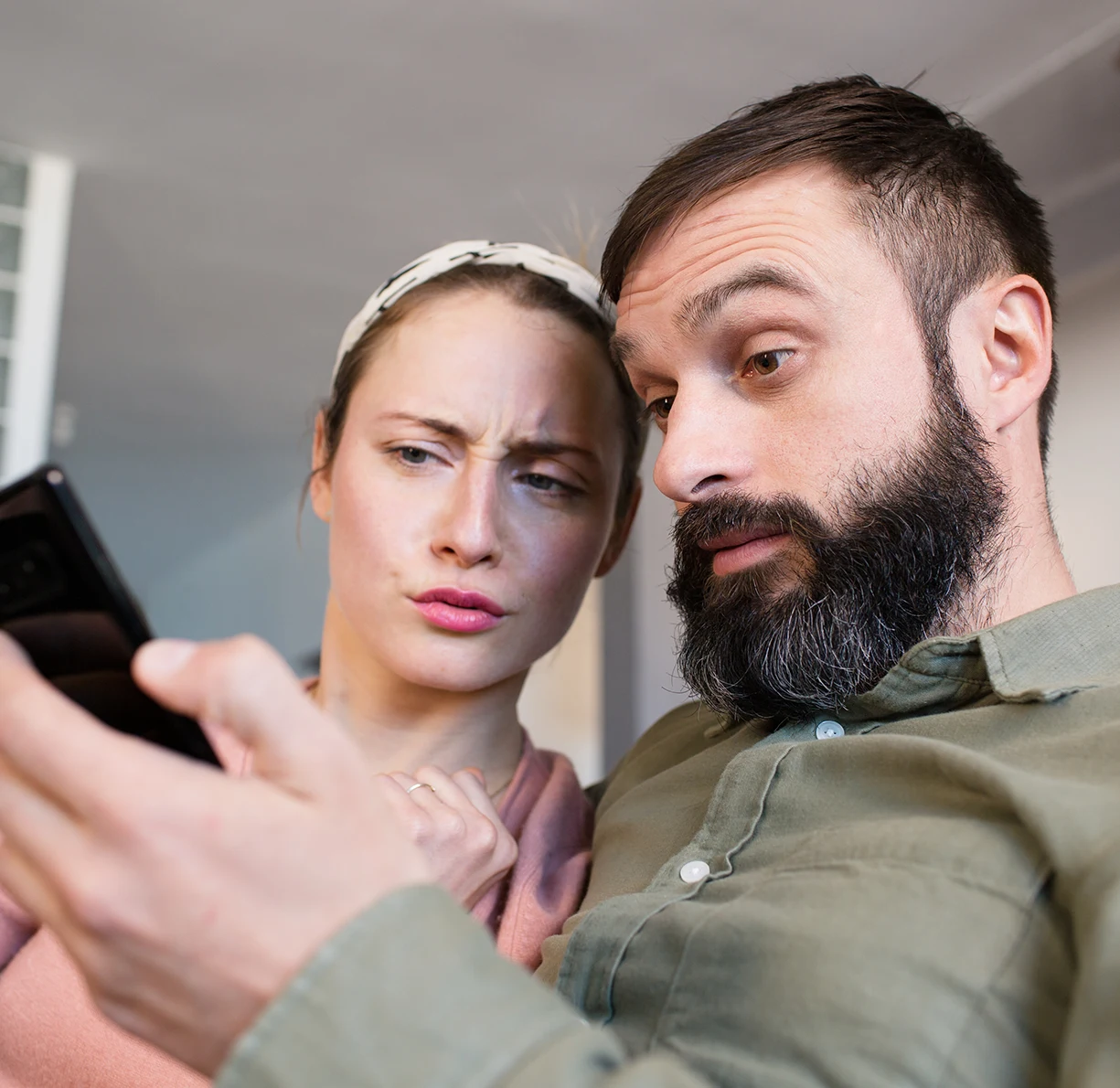 Zwei Eltern, die verwirrt auf das Smartphone mit WhatsApp schauen.